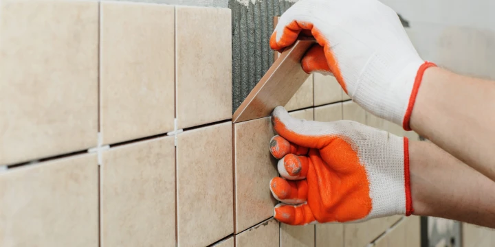 Worker  putting  tiles on the wall in the kitchen.
